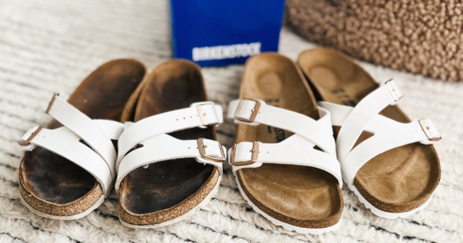 older pair of white Birkenstock sandals, worn in and brand new pair next to each other, with a Birkenstock shoe box behind them