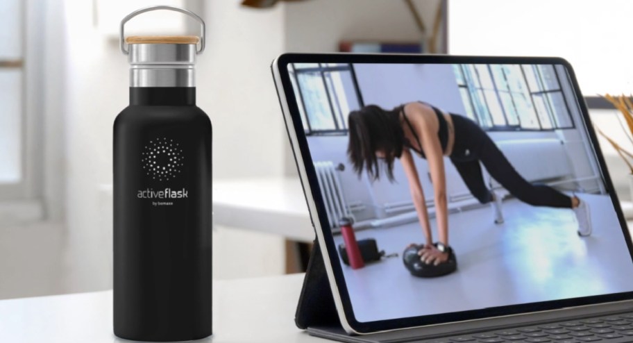Black large water bottle next to laptop