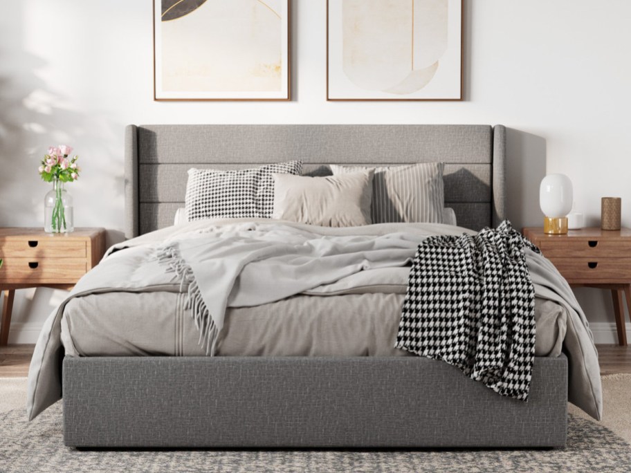 Stylish bedroom with a gray upholstered bed, layered pillows, and a houndstooth throw.
