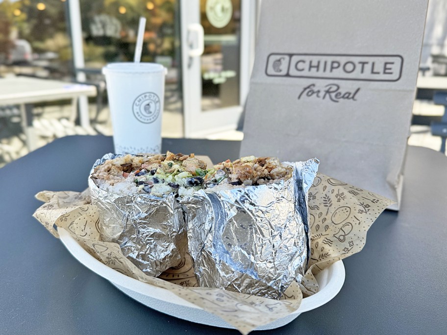 chipotle burrito displayed in front of a to-go bag and drink cup