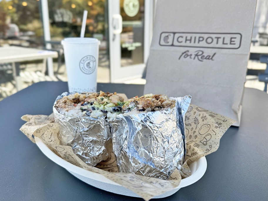 chipotle burrito displayed in front of a to-go bag and drink cup