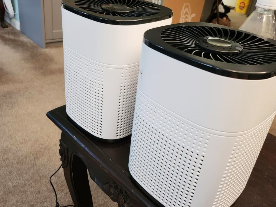 two white and black air purifiers on table