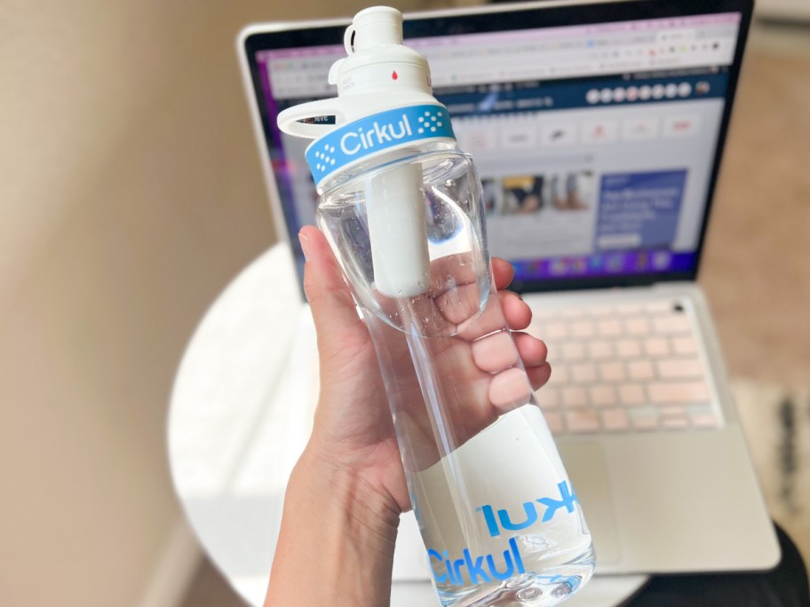 Cirkul water bottle in woman's hand with computer in the background