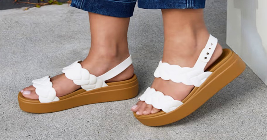 woman wearing pair of crocs wedges with white braided straps