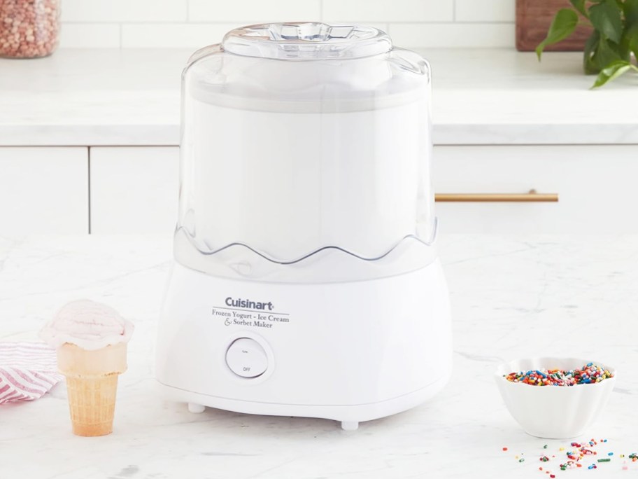 white ice cream maker on counter near sprinkles and ice cream cone