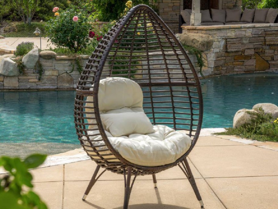 Egg chair displayed outside with a pool background