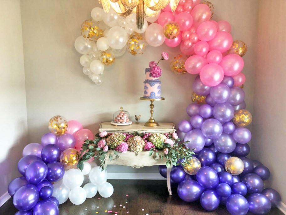 pink, purple, gold and white balloon arch around table with cake