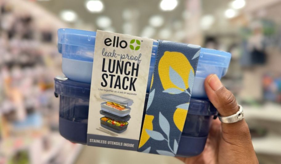 a womans hand holding blue Ello lunch container stack