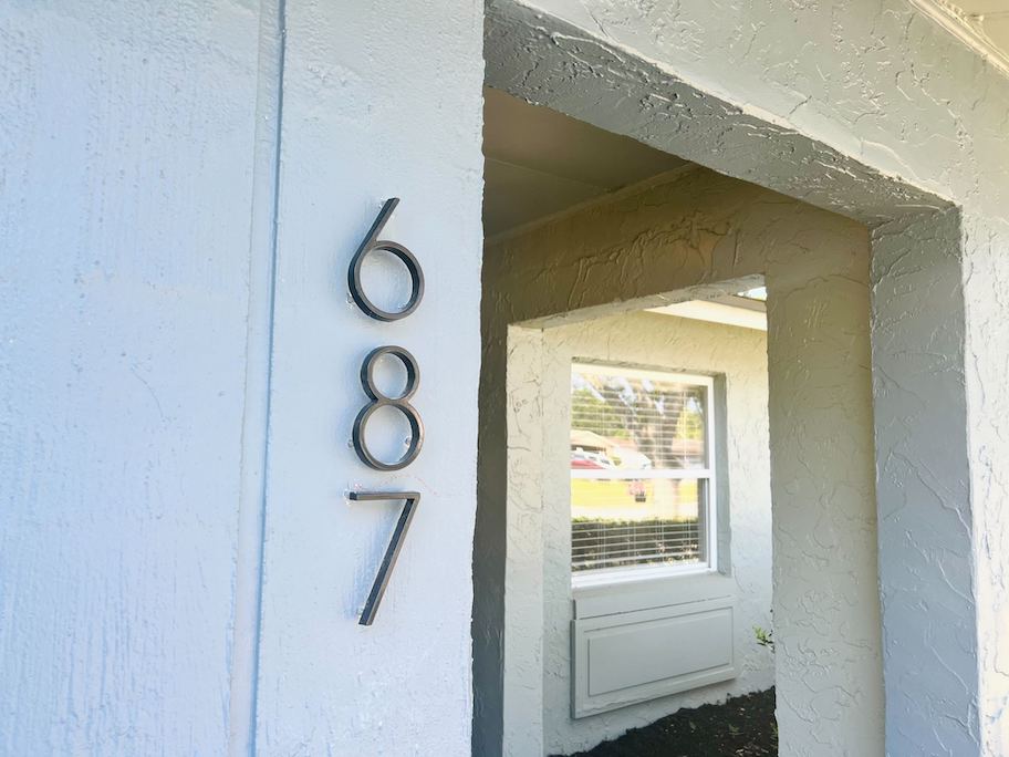 black modern floating house numbers on stucco home