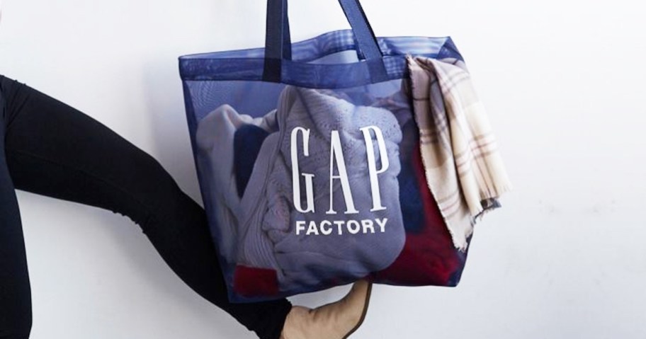 woman balancing blue GAP Factory shopping bag on her foot