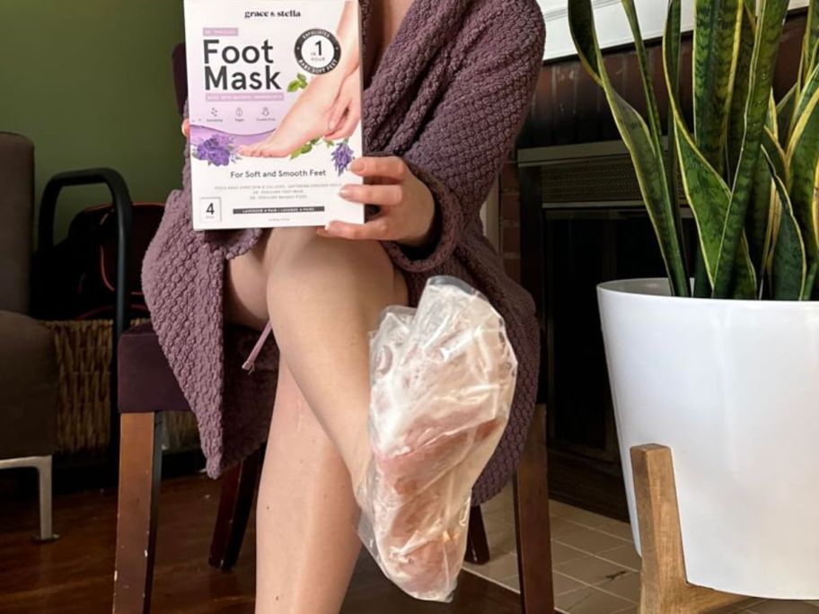 Woman wearing a Grace & Stella foot mask while holding up the box