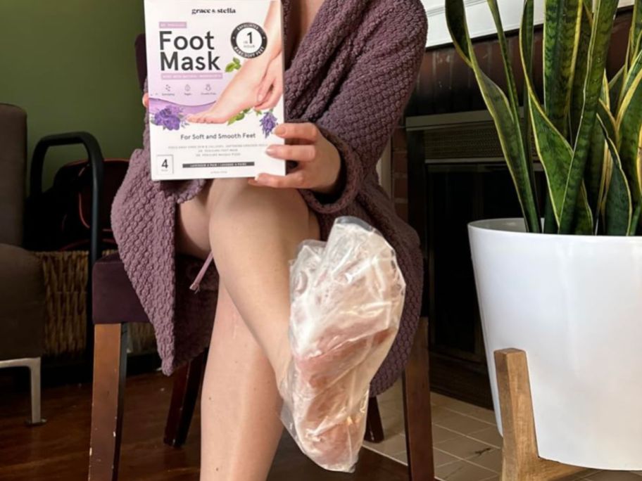 Woman wearing a Grace & Stella foot mask while holding up the box
