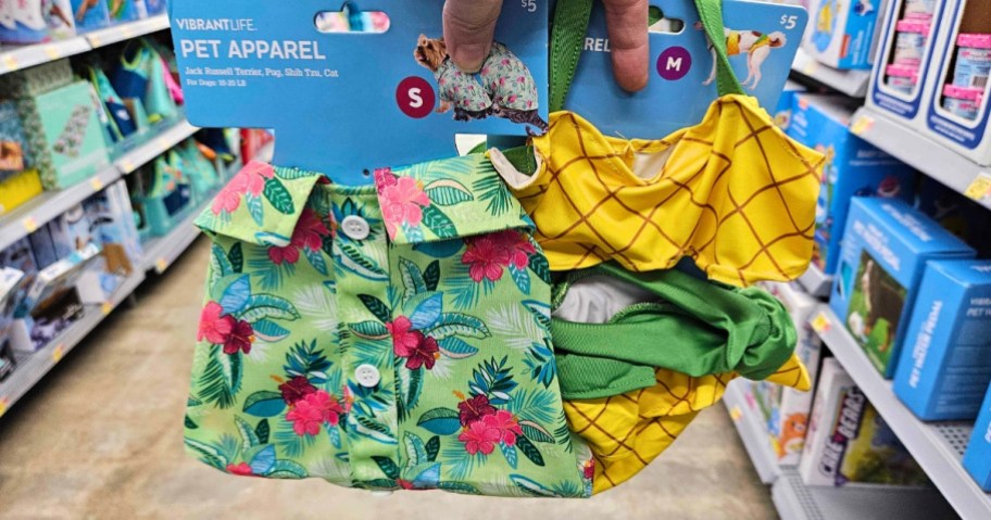 hand holding up a pet Hawaiian style shirt and a pet pineapple bikini