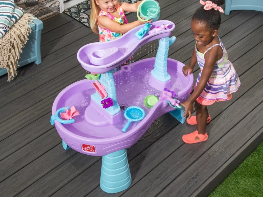 kids playing with a purple and blue Step2 Water Table on a back deck