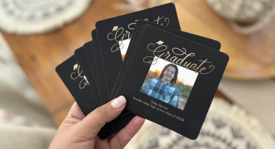 Hand holding graduation coasters with image of kiddos