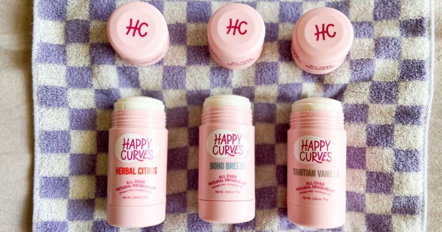 3 Happy Curves Deodorants on a checkered towel with the lids off