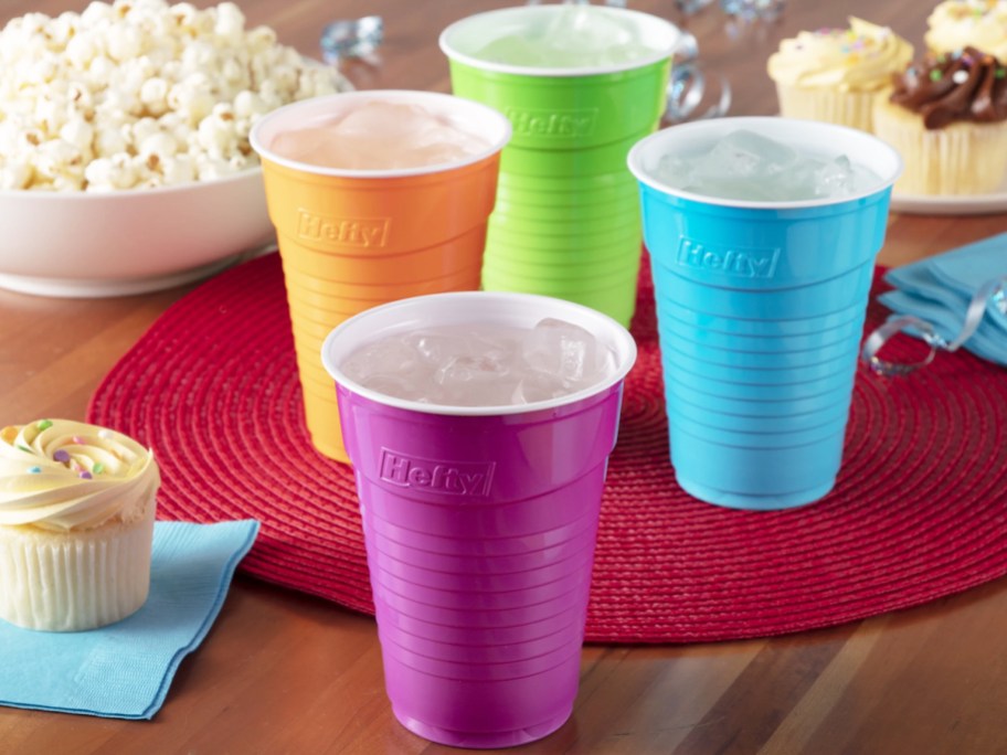 purple, orange, blue, and green disposable cups on table filled with ice water