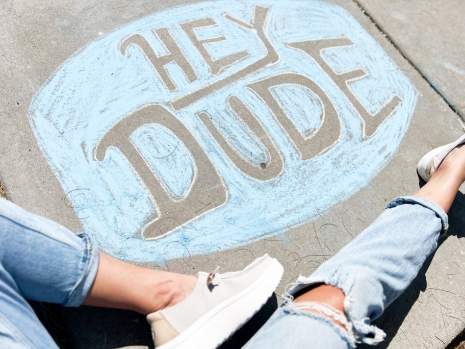 woman sitting next to hey dude logo in chalk in sidewalk