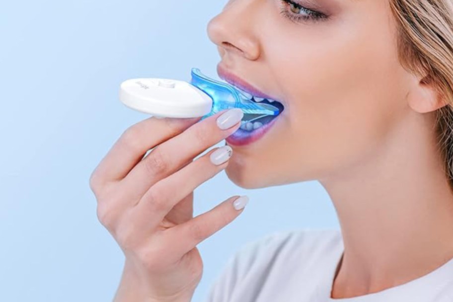 woman using LED teeth whitening tool 