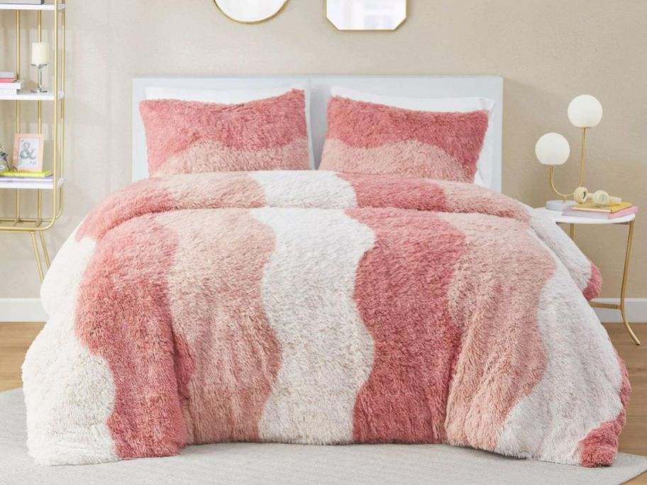 A bed with an Intelligent Design Rachel Ombre Shaggy Faux Fur Comforter Set in pink