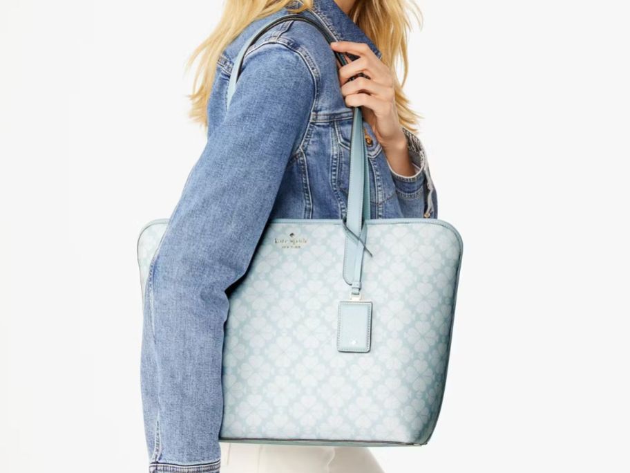 A woman with a blue Kate Spade Signature Spade Flower Tote