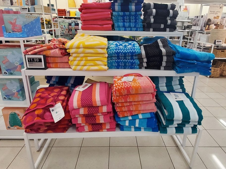 display table full of folded beach towels in various colors