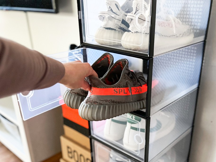 taking pair of sneakers out from stacked clear storage boxes
