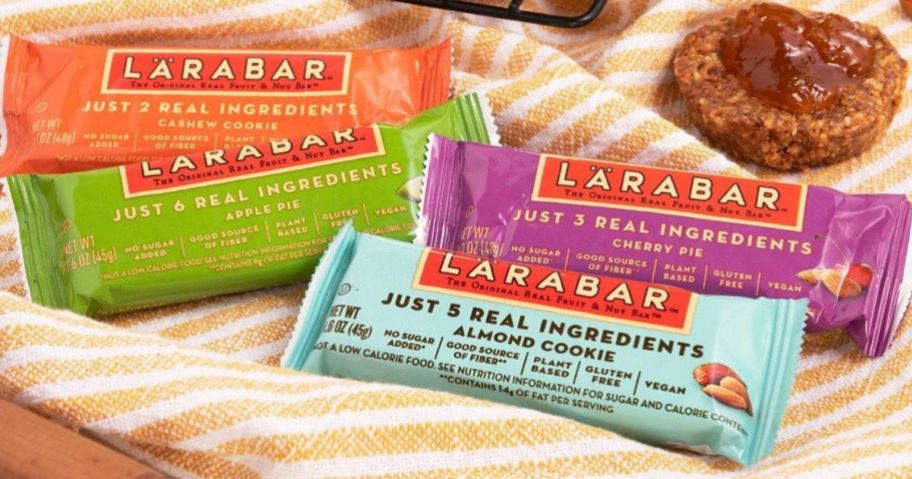 Assorted flavors of Larabar bard on a kitchen towel next to a cookie