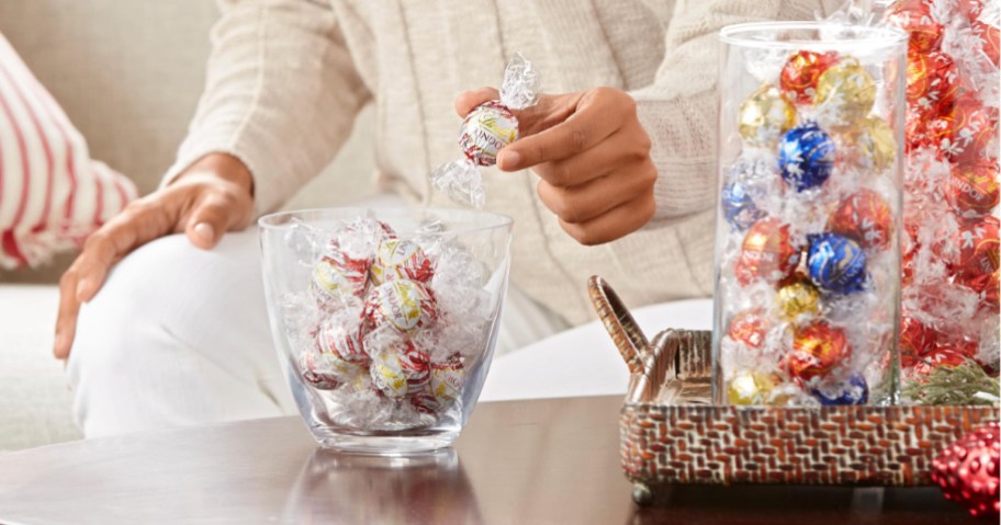 person taking Lindt chocolate candy from glass candy bowl