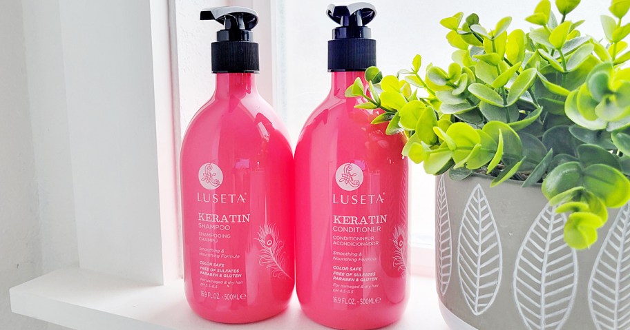 pink luseta keratin shampoo and conditioner bottles on windowsill near plant