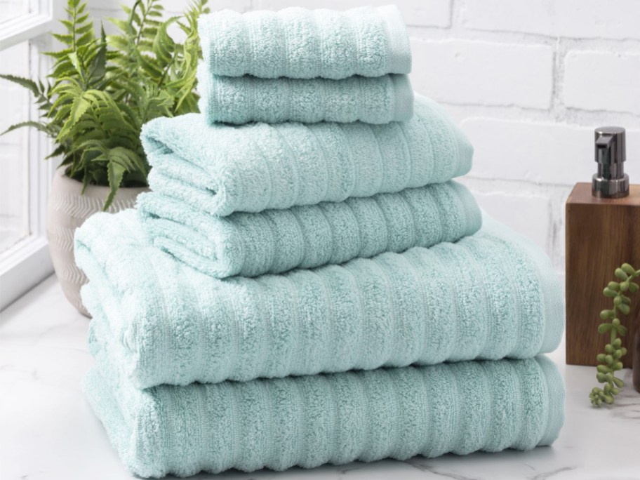 stack of light blue ribbed bath towels and wash cloths on bathroom counter