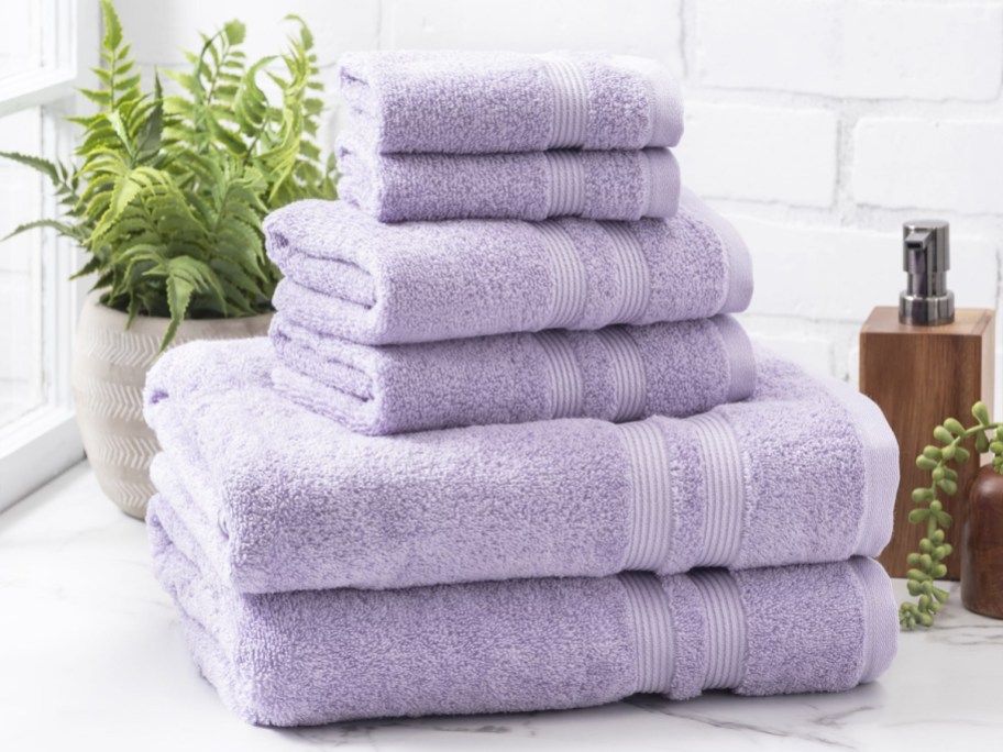 stack of light purple bath towels and wash cloths on bathroom counter