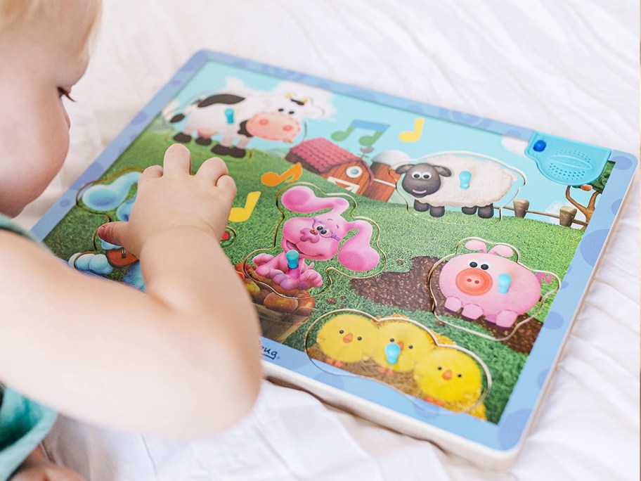 toddler playing with wooden Blue's Clues puzzle