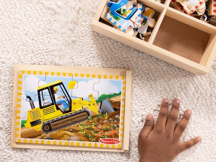 child completing a construction vehicle wooden puzzle