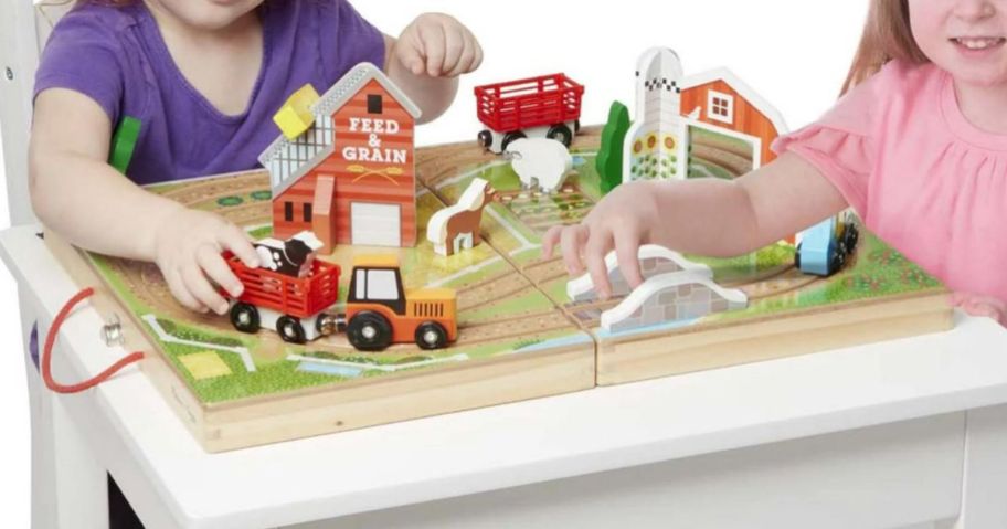 2 kids playing with a Melissa & Doug Farm on a table