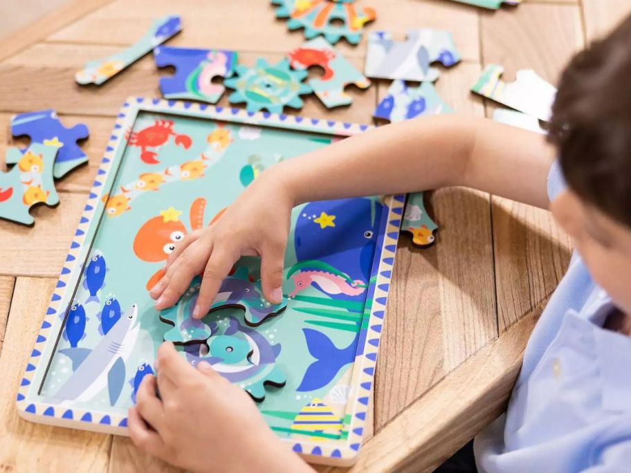 boy playing with Melissa & Doug Wooden Underwater Jigsaw Spinning Gear Puzzle