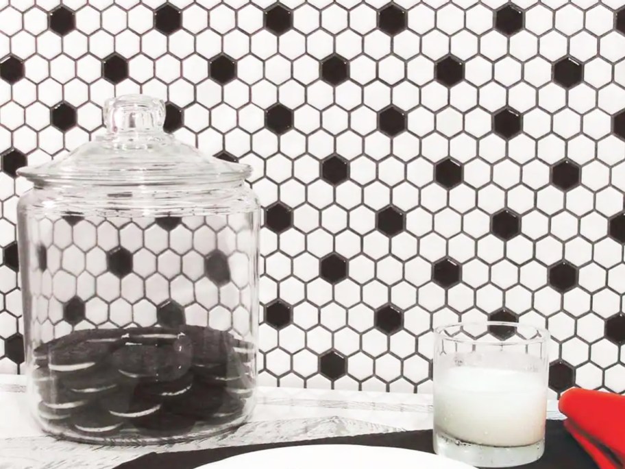 jar of cookies and glass of milk near white and black backsplash