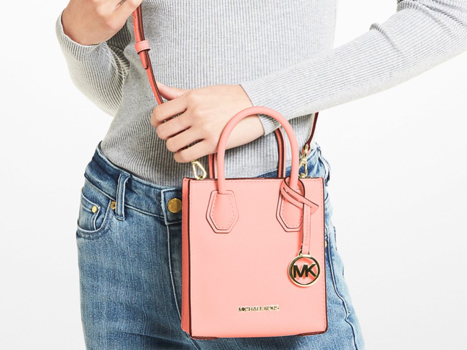 woman in grey top and jeans with light pink crossbody bag