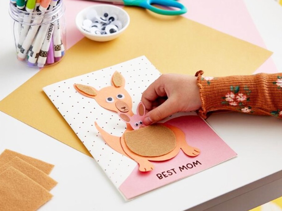 child making a kangaroo card that says "best mom"