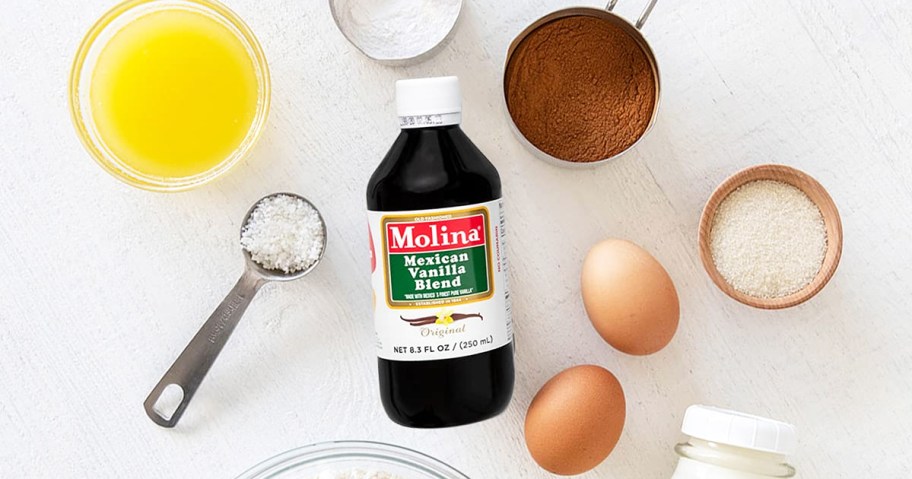 bottle of Molina Mexican Vanilla Blend Extract surrounded by measuring cups and baking ingredients 