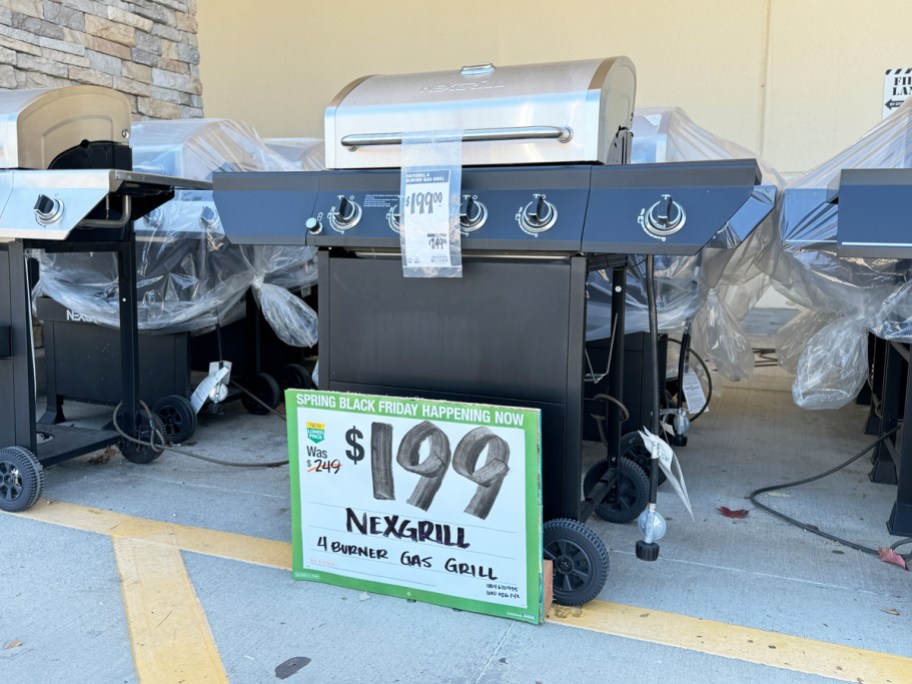 silver and back propane grill on display in front of home depot store with $199 sale sign