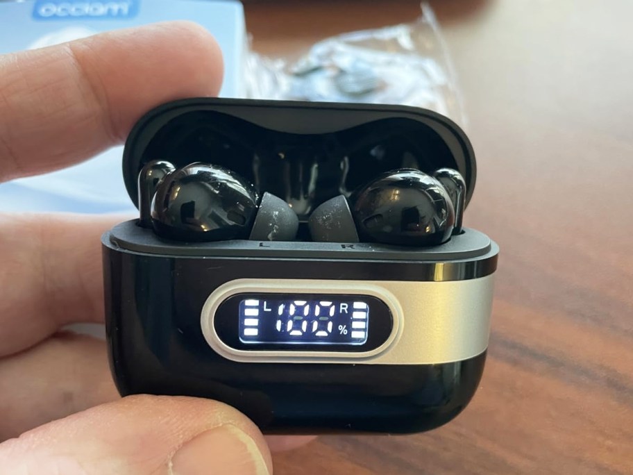 hand holding a black earbuds charging case with earbuds inside