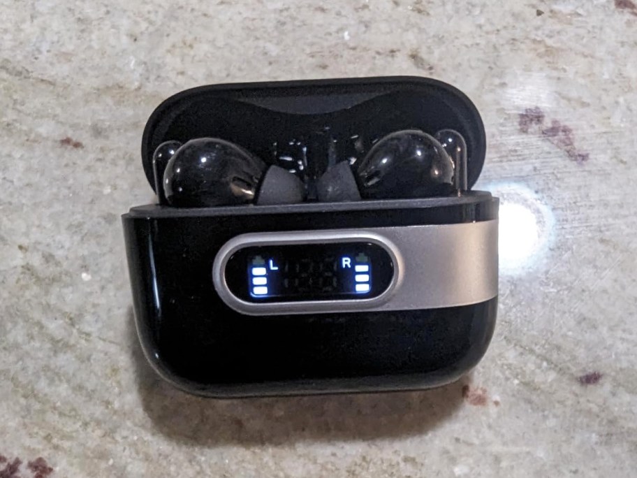 black earbuds inside charging case on counter