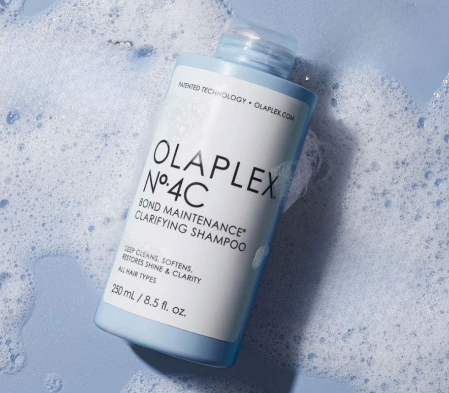 a bottle of olaplex no 4C clarifying shampoo on a background of shampoo suds.