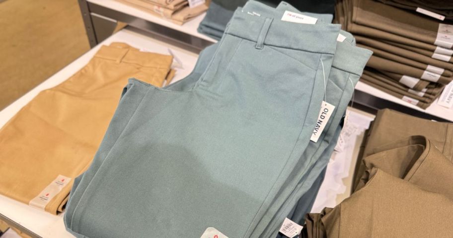 a stack of Women's pants folded on a table at old navy