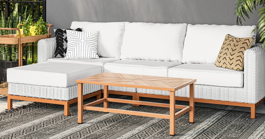 white patio couch with wood table on area rug