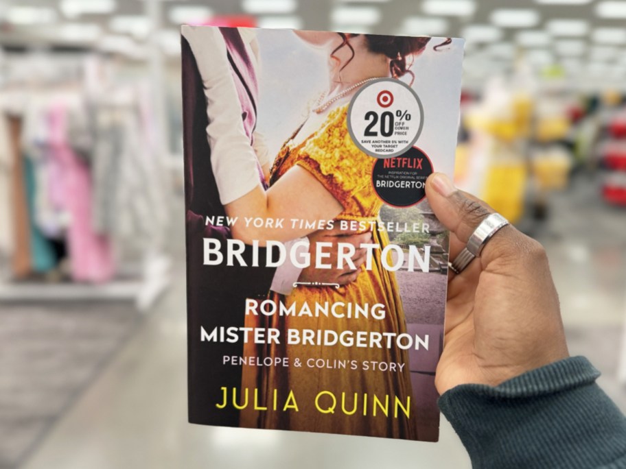 hand holding up Romancing Mister Bridgerton Paperback Book in store