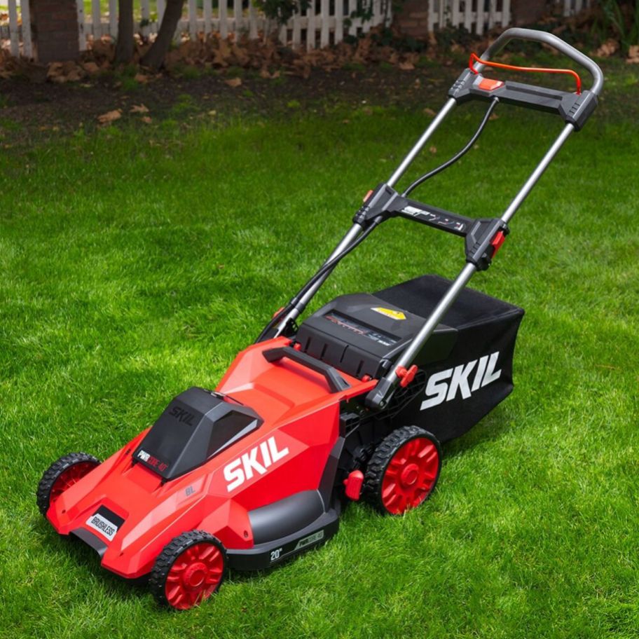 a red battery powered lawn mower with bag on a lawn