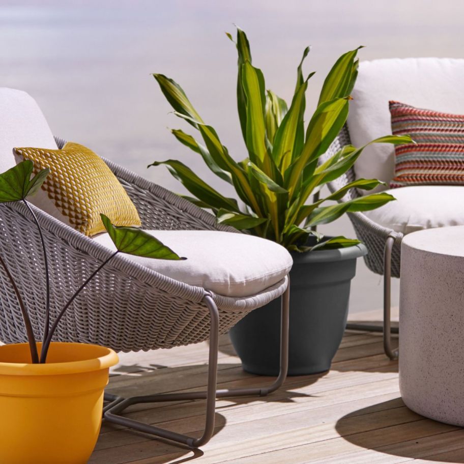 two plastic planters arranged on a patio with wicker furniture