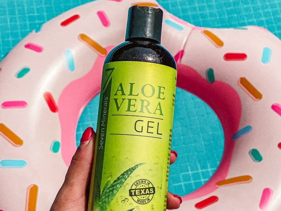 holding a bottle of Seven Minerals Organic Aloe Vera Gel above a donut pool float